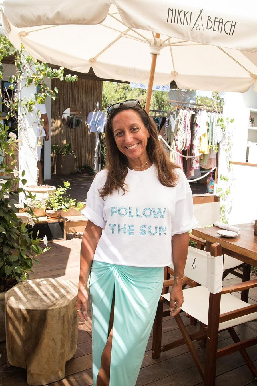 Shot with the foreground Fashion consultant Giorgia Viola, smiling and wearing a white T-shirt that mentions "follow the sun" , the name of the Pop-Up luxury shop she created.